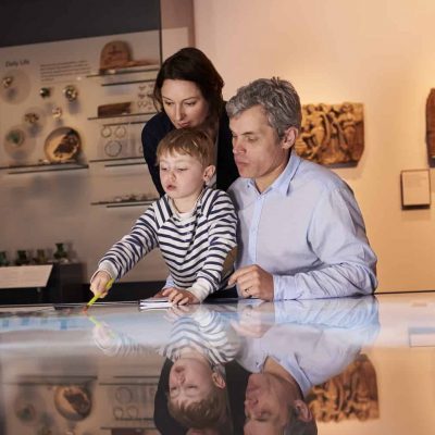 Family On Trip To Museum Looking At Map Together